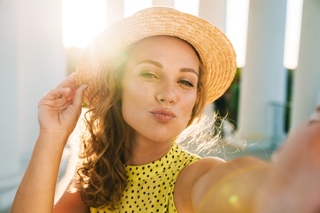 A photo of a pretty woman wearing a straw hat in the sun