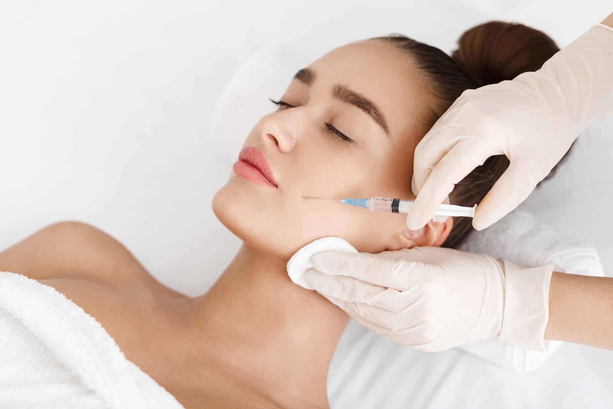 A brunette woman getting a Botox injection in her face