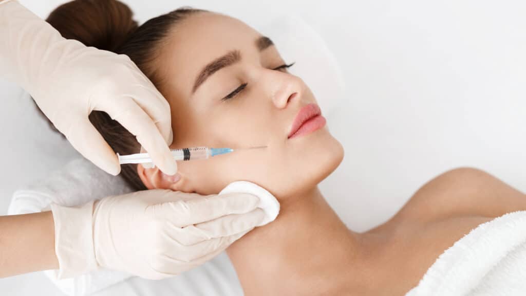A brunette woman getting a Botox injection in her face